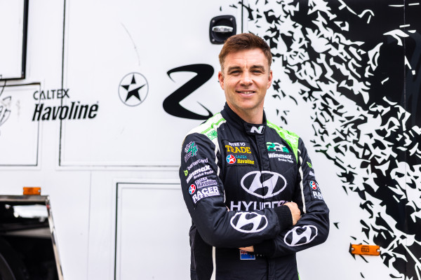 Hayden Paddon in his race suit standing in front of his Caltex Havoline branded truck